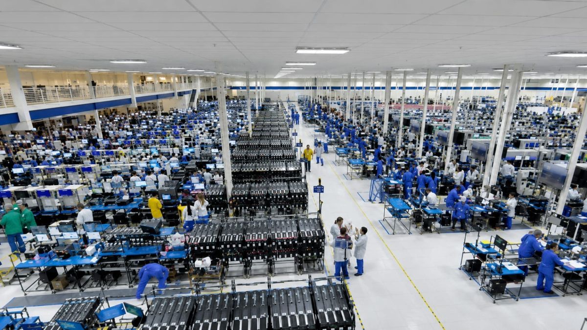 Linha de produção de smartphones em uma fábrica, com equipamentos modernos e funcionários em atividade