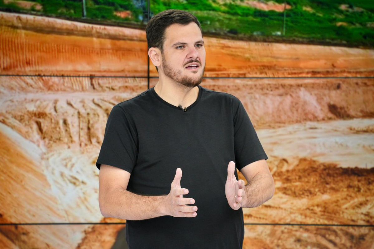 O prefeito de Manaus, Renato Junior, gesticula durante pronunciamento em frente a um painel com imagem de obras.
