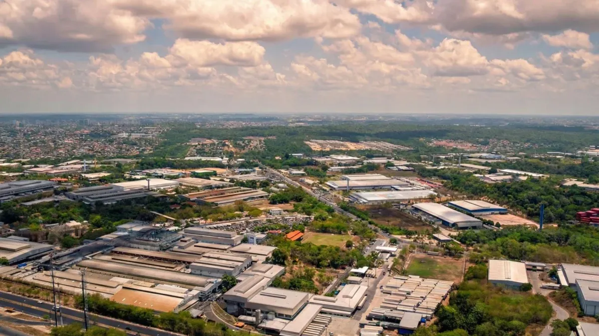 Vista aérea do Polo Industrial de Manaus, com galpões e fábricas em meio à vegetação e uma rodovia