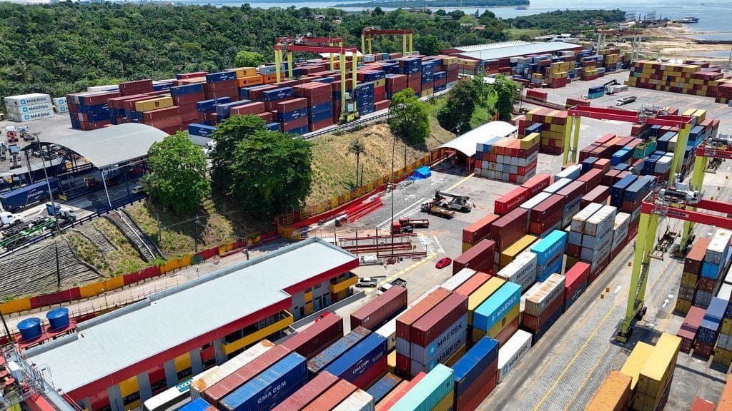 Contêineres empilhados em um terminal portuário, simbolizando importação e comércio exterior.