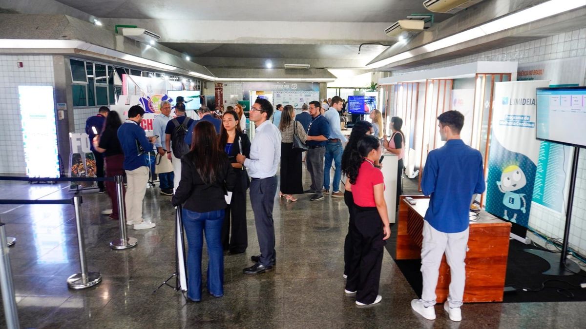 Pessoas circulam entre estandes e painéis informativos no saguão do Auditório da Suframa durante evento em Manaus.