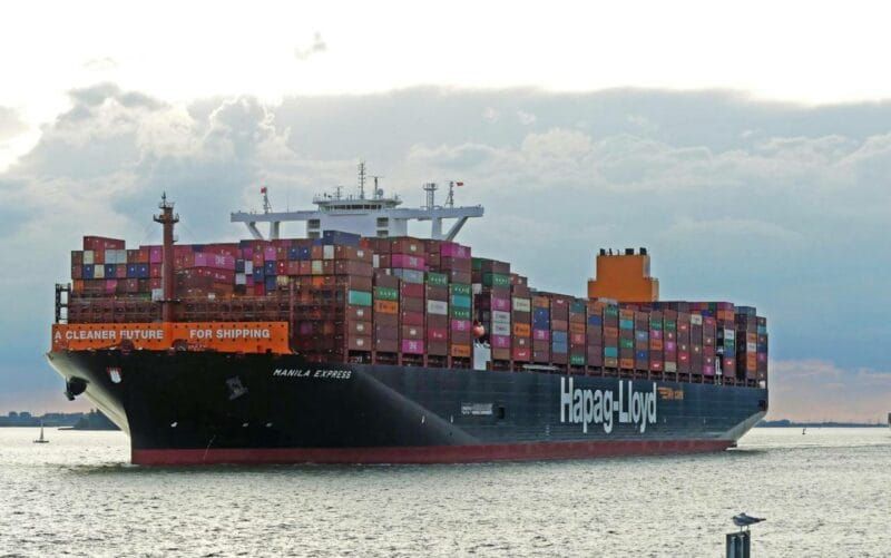 Navio porta-contêineres Manila Express da armadora Hapag-Lloyd navegando em águas abertas sob céu nublado.