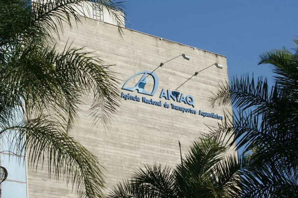 Fachada do prédio da Antaq, Agência Nacional de Transportes Aquaviários, com letreiro azul em parede de concreto e palmeiras.