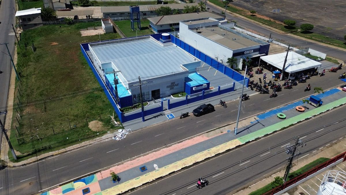 Vista aérea do Escritório Regional do Sebrae em Coari, prédio branco com detalhes em azul localizado em avenida movimentada.