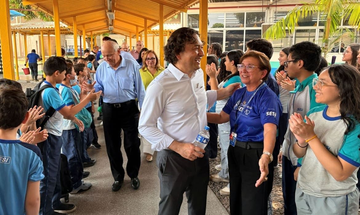 Fausto Augusto Junior e Antonio Silva caminham entre estudantes uniformizados em uma unidade do Sesi em Manaus.