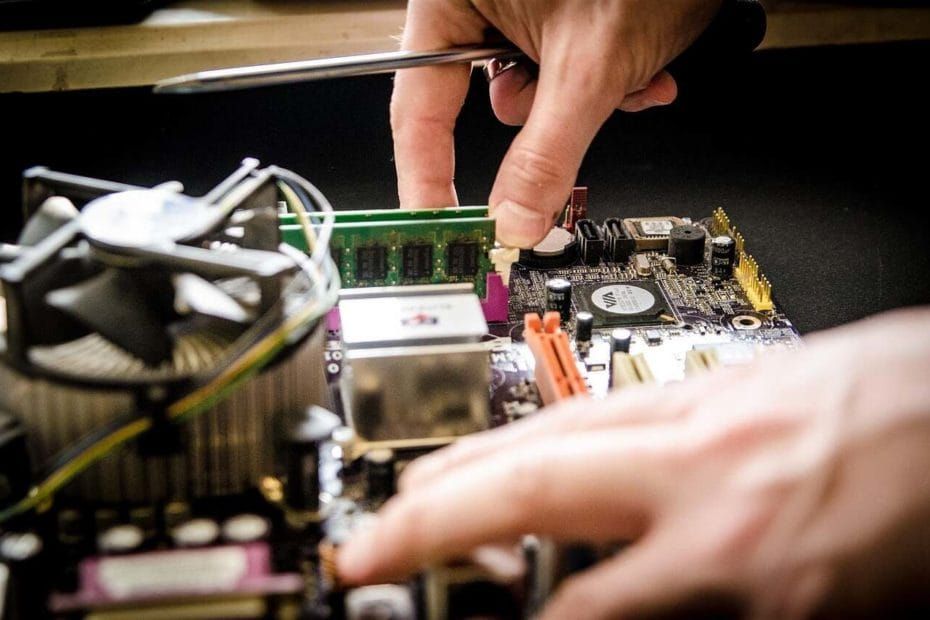 Mãos manuseando placa de circuito eletrônico com instalação de pente de memória e ferramentas de precisão.
