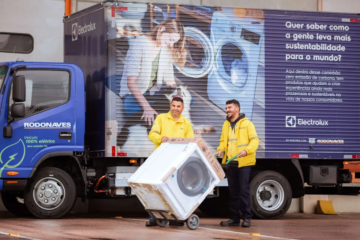 Dois entregadores descarregam uma máquina de lavar de um caminhão elétrico da Rodonaves em parceria com a Electrolux.