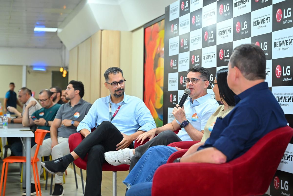David Almeida fala ao microfone sentado em poltrona vermelha durante encontro na fábrica da LG em Manaus.