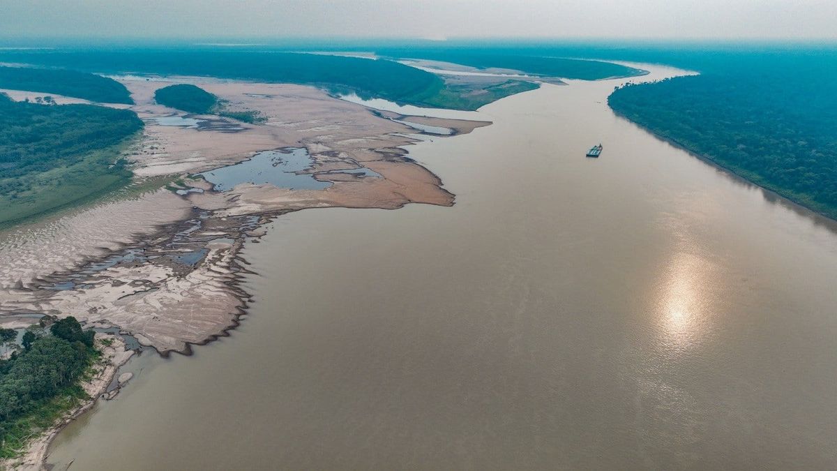 Vista aérea de rio com nível baixo de água e grandes bancos de areia expostos na margem esquerda, cercado por floresta.