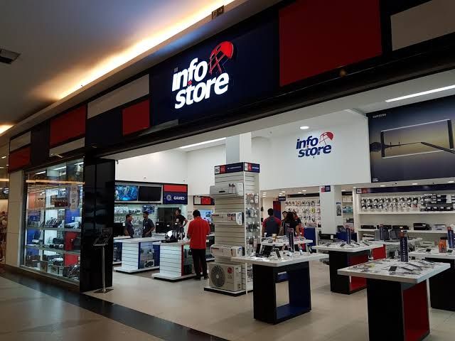 Fachada e interior da loja Info Store em um shopping de Manaus, com balcões de atendimento e produtos de tecnologia.