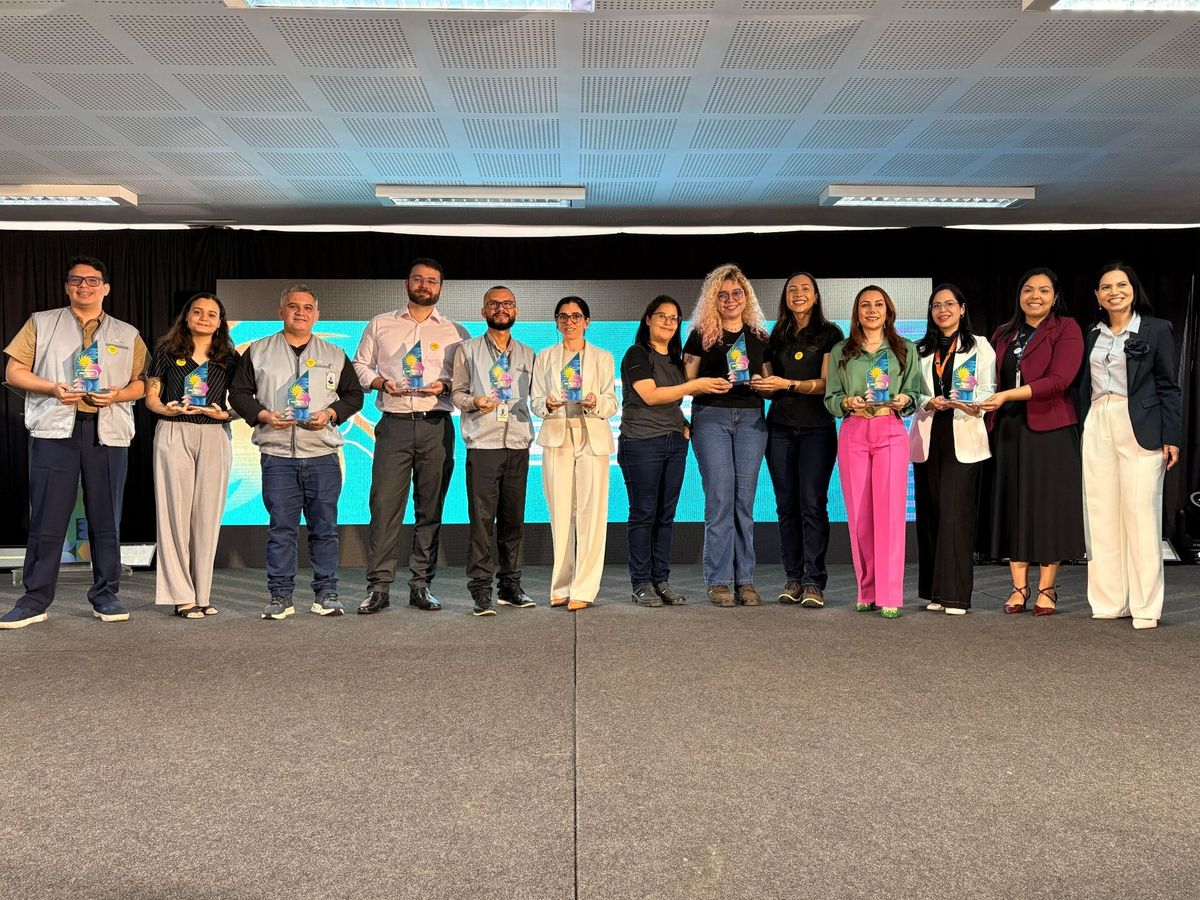 Grupo de premiados segurando troféus transparentes no palco durante a entrega do Prêmio IEL 2026 em Manaus.