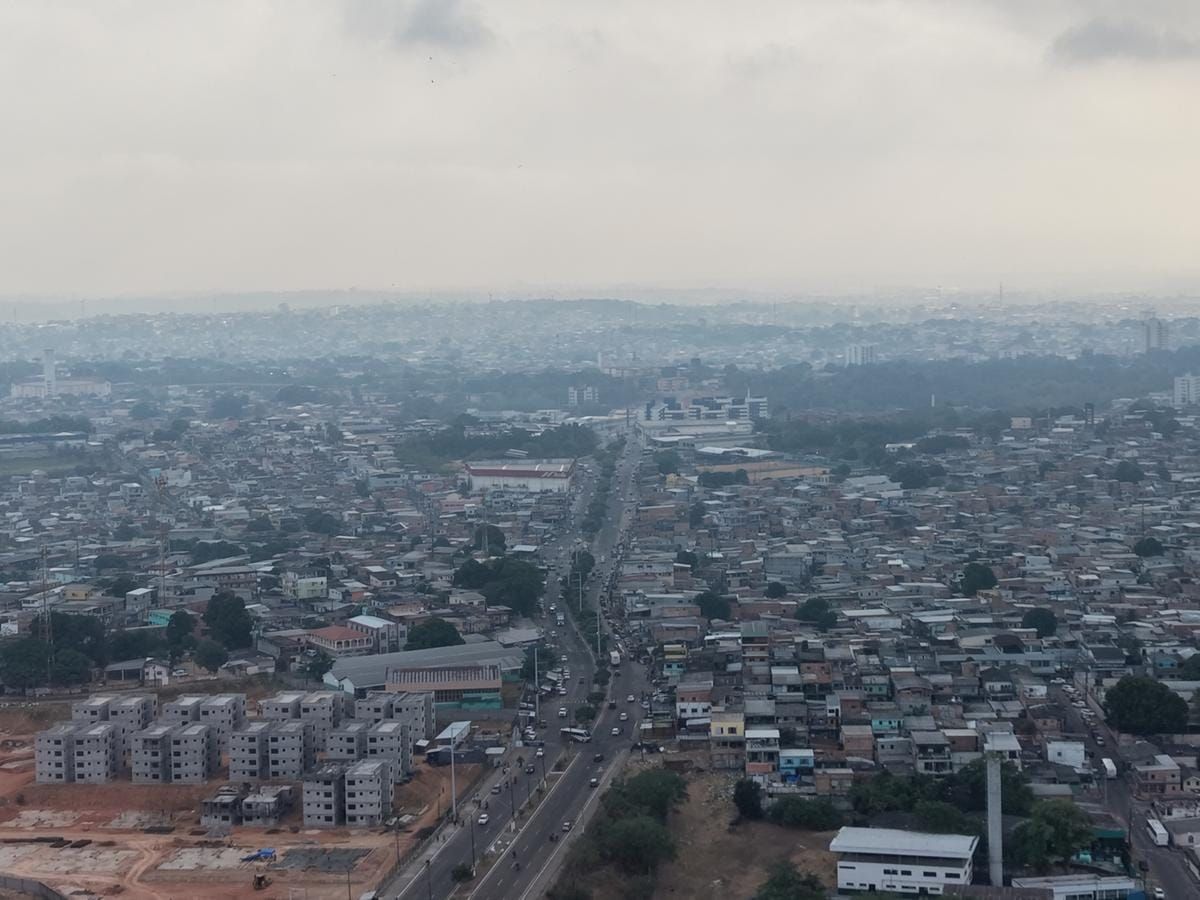 Vista aérea de Manaus coberta por fumaça cinzenta, com prédios e casas sob céu nublado em 17 de setembro de 2026.