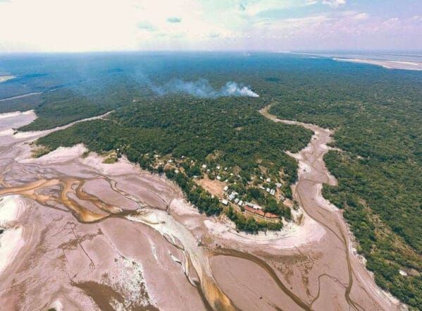 Vista aérea de rio com leito seco e bancos de areia expostos cercado por floresta na Amazônia.