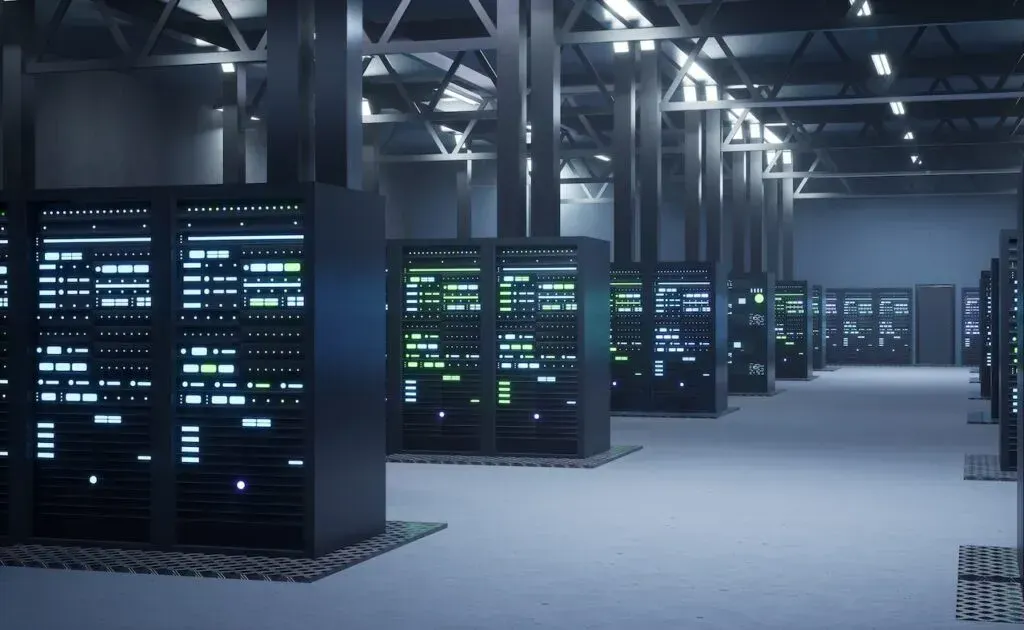 Corredores de um data center com diversos racks de servidores iluminados por luzes verdes e brancas em ambiente industrial.