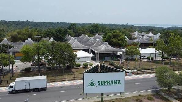 Vista aérea da sede da Suframa em Manaus, com placa da autarquia em primeiro plano e caminhão baú branco na via lateral.