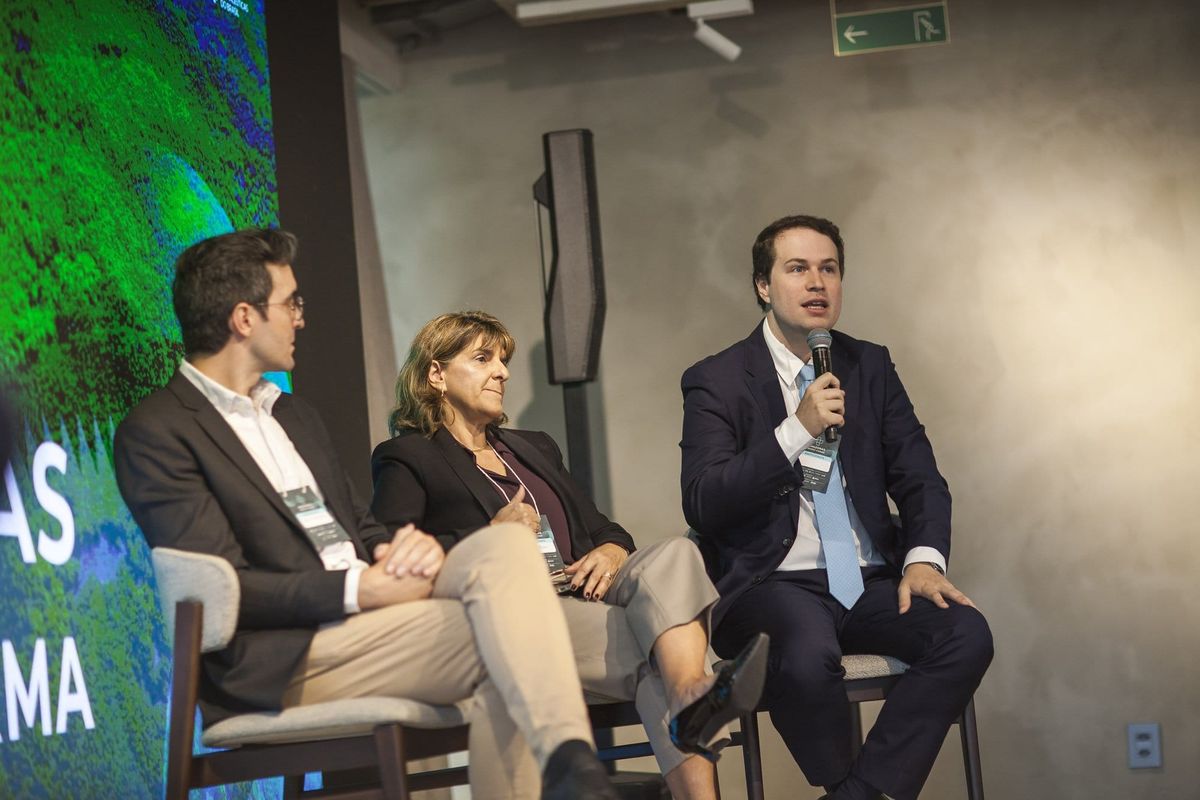 João Victor Aguiar fala ao microfone em painel ao lado de Otávio Meneguette e Isabel Reis no Amazonas Invest Farma.