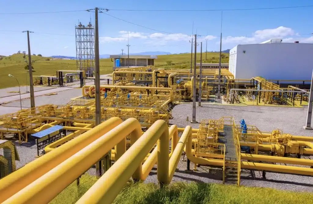 Tubulações amarelas e infraestrutura de processamento de gás natural em unidade industrial ao ar livre.