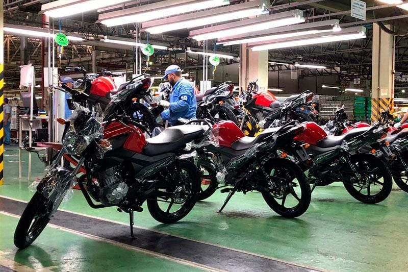 Linha de montagem de motocicletas da Yamaha no Polo Industrial de Manaus, com operário trabalhando em modelos vermelhos.