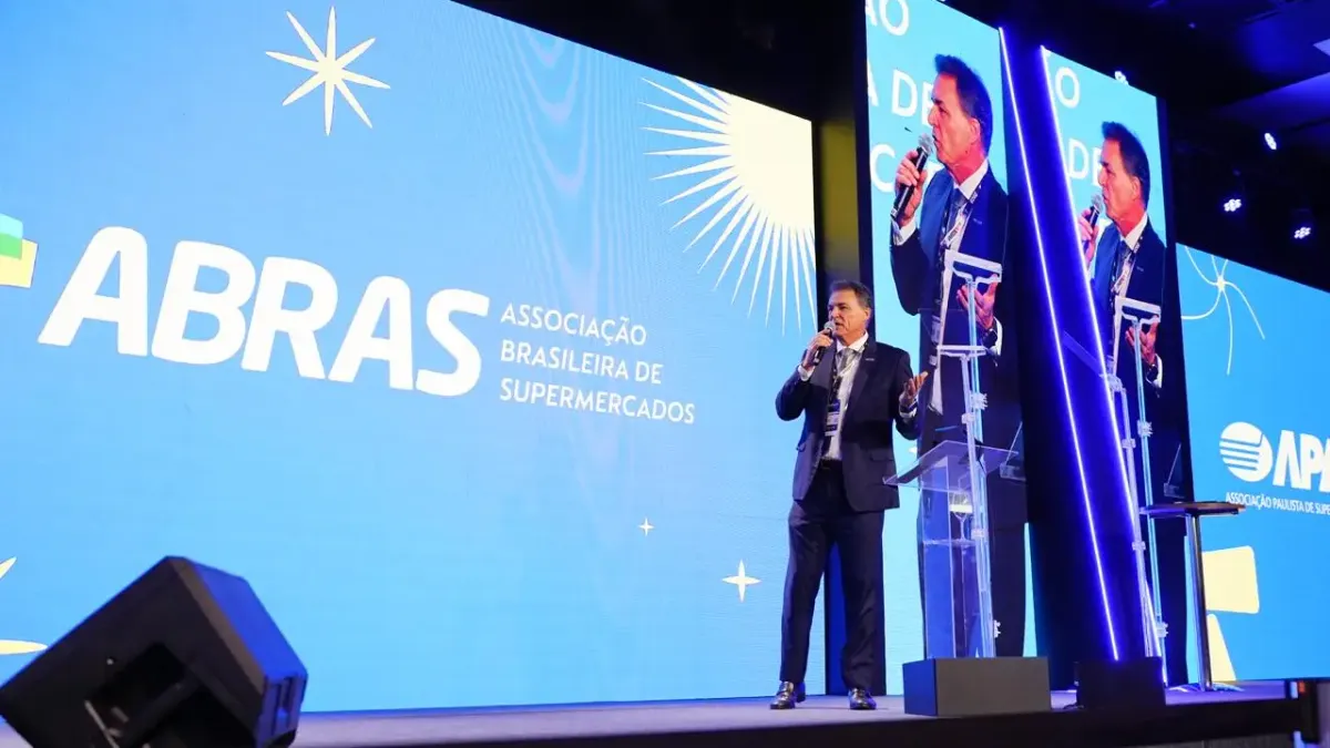 João Galassi, presidente da Abras, discursa em palco com telão ao fundo exibindo a logomarca da associação.