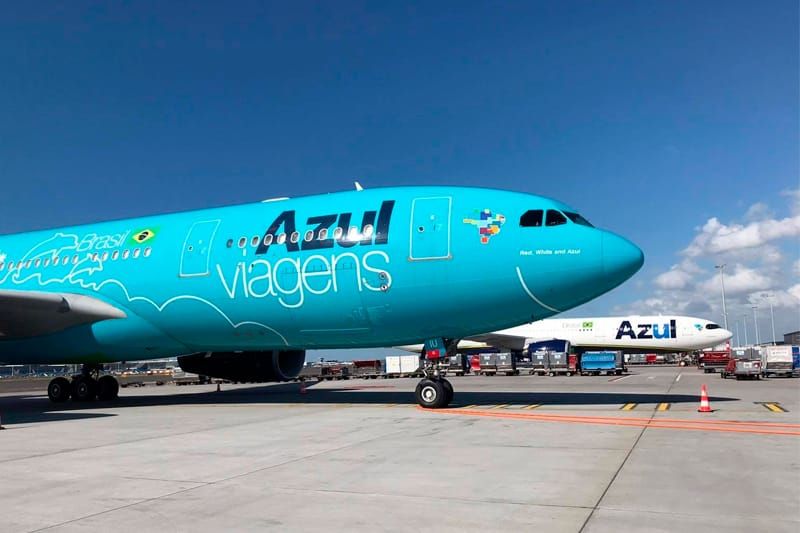 Aeronave azul da Azul Viagens estacionada em pátio de aeroporto sob céu limpo.