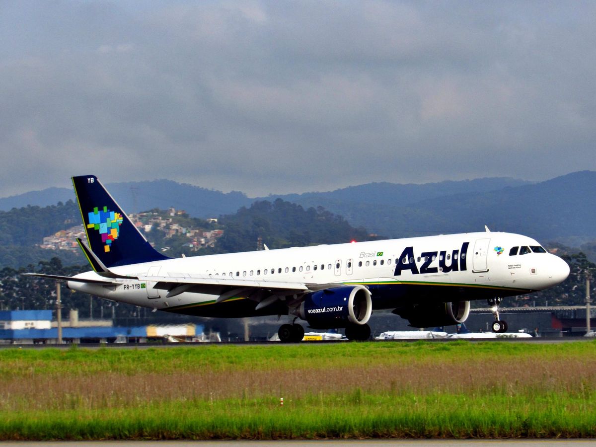 Aeronave da Azul Linhas Aéreas taxiando em pista de aeroporto com montanhas ao fundo sob céu nublado.