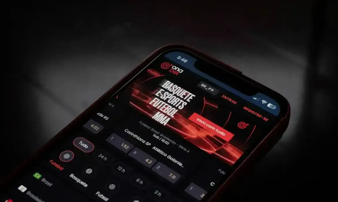 Celular exibindo interface de aplicativo de apostas esportivas com opções de futebol, basquete e MMA.