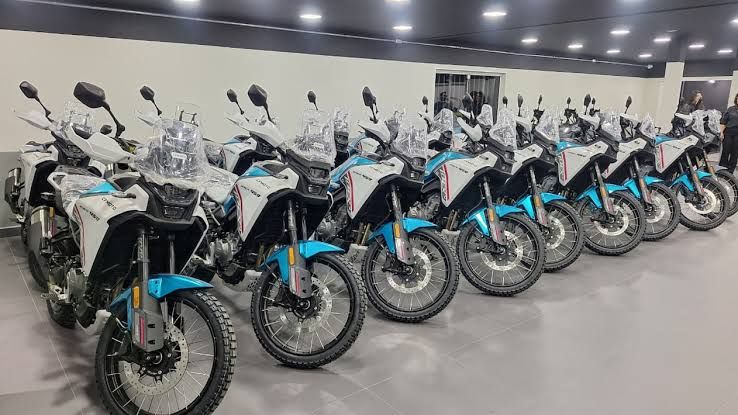 Fileira de motocicletas Ibex 450 da CFMOTO, nas cores branco e azul, estacionadas em um showroom.