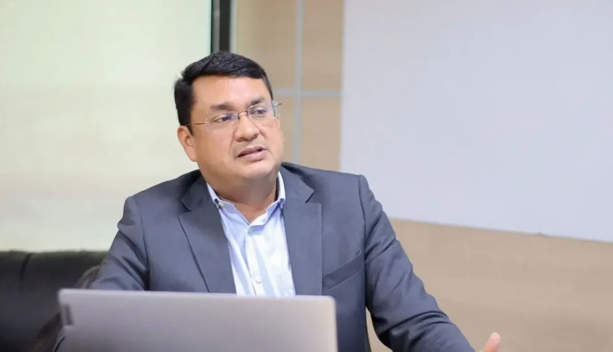O economista Márcio Paixão, de óculos e terno cinza, fala sentado à frente de um notebook em um escritório.