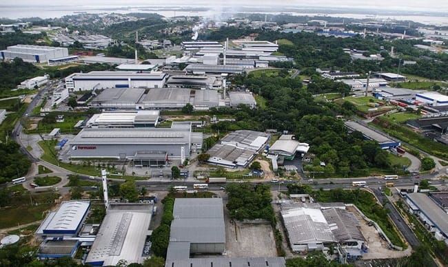 Vista aérea de galpões industriais e fábricas cercados por vegetação no Polo Industrial de Manaus.
