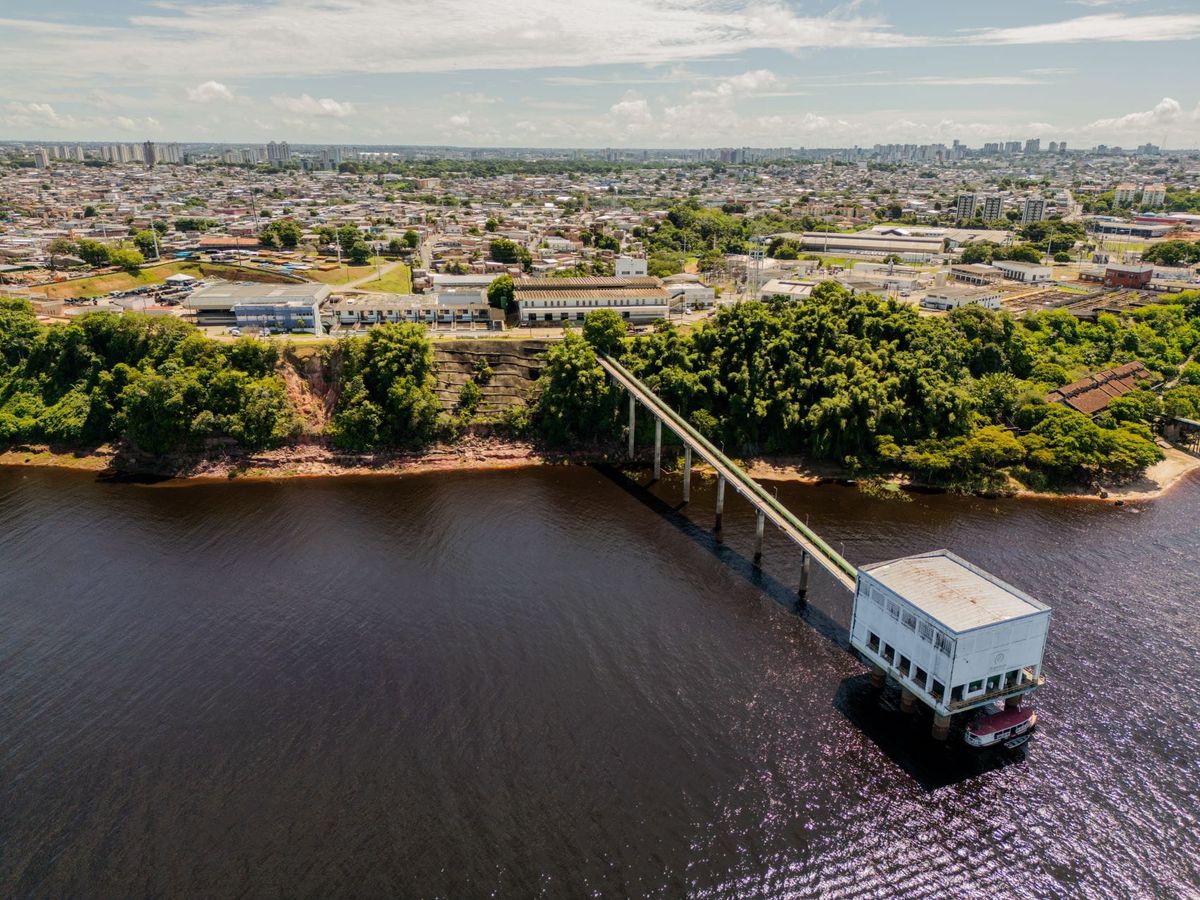 Vista aérea da estação de captação de água da Águas de Manaus avançando sobre as águas escuras do Rio Negro.