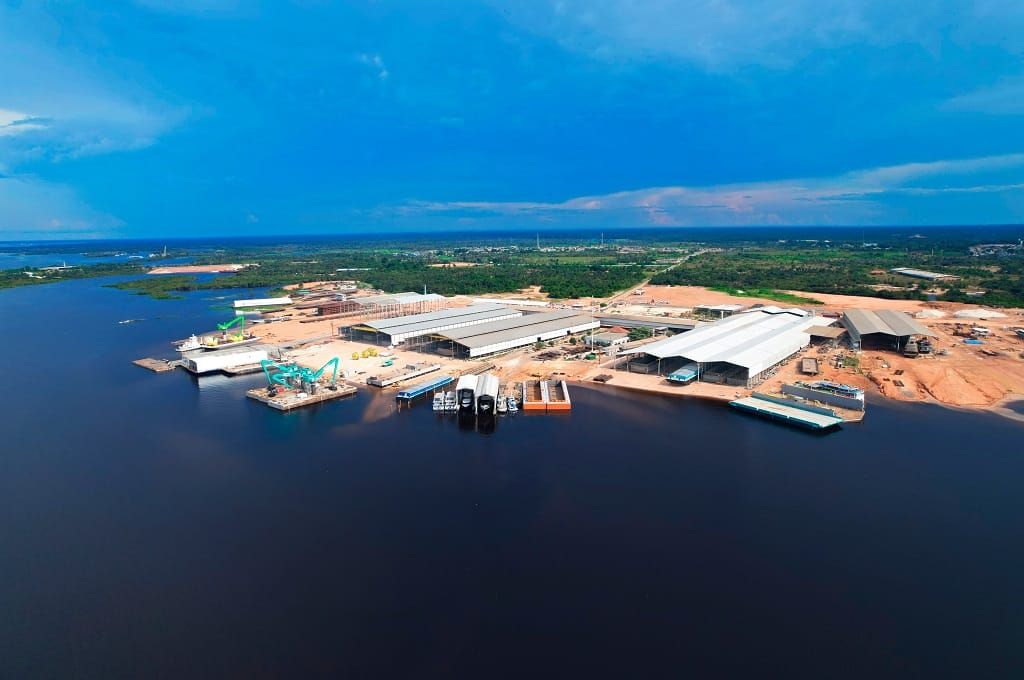 Vista aérea do Estaleiro Juruá em Iranduba, com galpões industriais e embarcações às margens do Rio Negro.