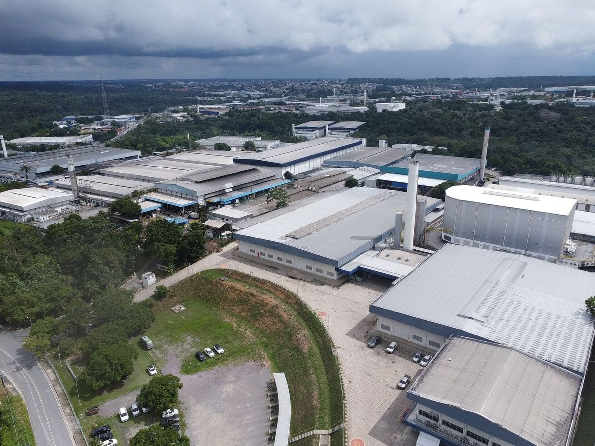 Vista aérea de galpões industriais e fábricas cercados por vegetação no Polo Industrial de Manaus.