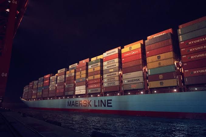 Navio porta-contêineres da Maersk Line carregado com unidades coloridas atracado em um porto durante a noite.