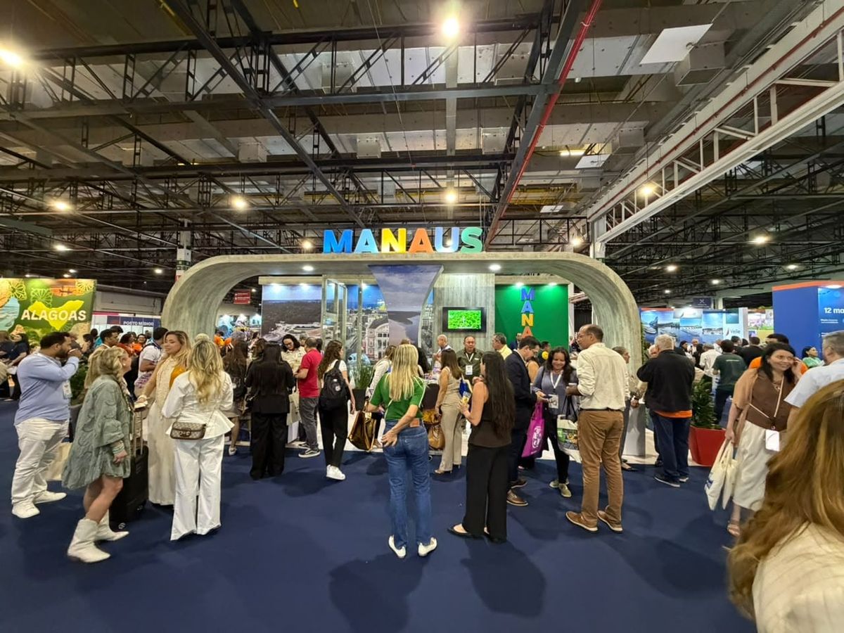 Pessoas visitam o estande de Manaus na 53ª Abav Expo, com letreiro colorido da cidade e imagens da capital amazonense.