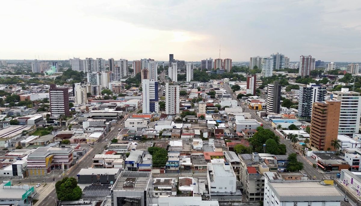 Vista aérea de prédios e casas no bairro Vieiralves, em Manaus, sob um céu nublado ao entardecer.