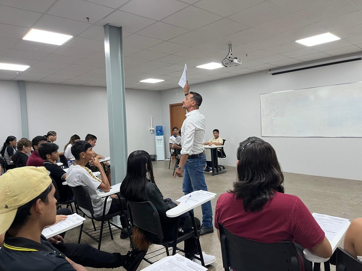 Instrutor em pé segurando papel diante de alunos sentados em sala de aula na Central do Empreendedor, em Manaus.