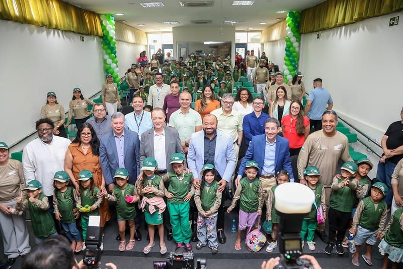 Representantes da Semed, Moto Honda e crianças uniformizadas em auditório durante lançamento de projeto ambiental.