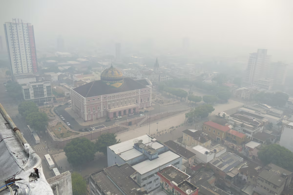 Vista aérea do Teatro Amazonas e arredores encobertos por densa camada de fumaça cinzenta em Manaus.