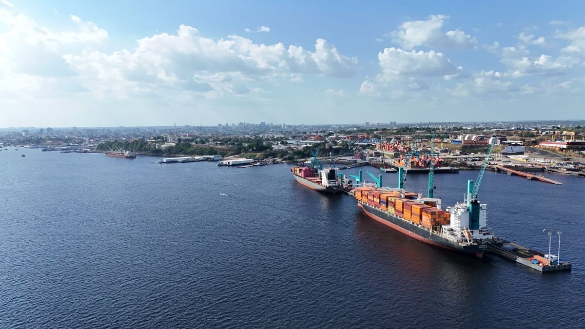 Navios cargueiros atracados no Super Terminais em Manaus, com guindastes operando contêineres sob céu aberto.