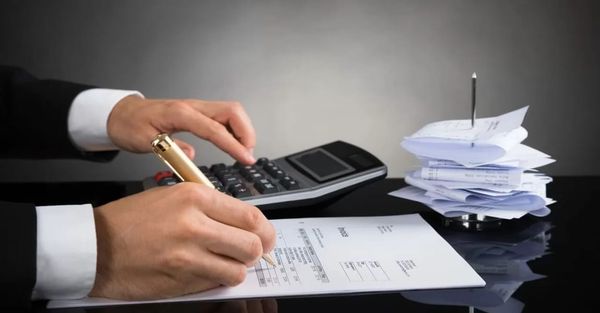 Mãos digitando em um teclado de notebook, com uma nota fiscal eletrônica (NF-e) em destaque na tela