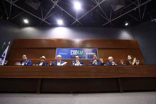 Membros do Conselho de Desenvolvimento do Estado do Amazonas (Codam) sentados em uma mesa de reunião, com um banner do Codam ao fundo