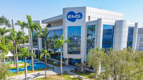 Fachada do edifício da EMS com vidros espelhados e logotipo azul, cercado por palmeiras e jardins.