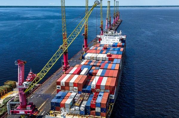 Embarcações e balsas de carga navegando em rio de grande porte no Amazonas, com margens de floresta