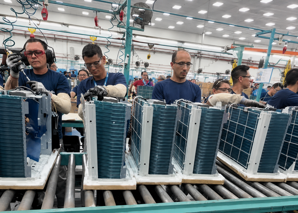 Linha de produção de aparelhos de ar-condicionado em fábrica no Polo Industrial de Manaus, com trabalhadores em suas posições