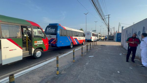 Ônibus de transporte especial parados em fila na rua, com dois homens conversando à direita, em Manaus