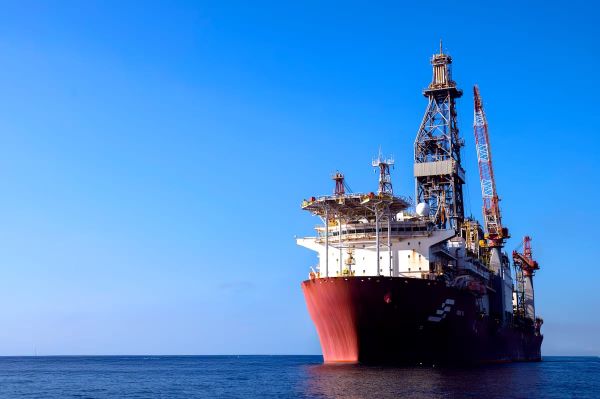 Plataforma de petróleo em alto mar, com o sol ao fundo, em operação de exploração