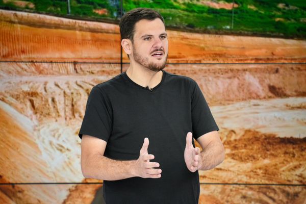 O prefeito de Manaus, Renato Junior, gesticula durante pronunciamento em frente a um painel com imagem de obras.