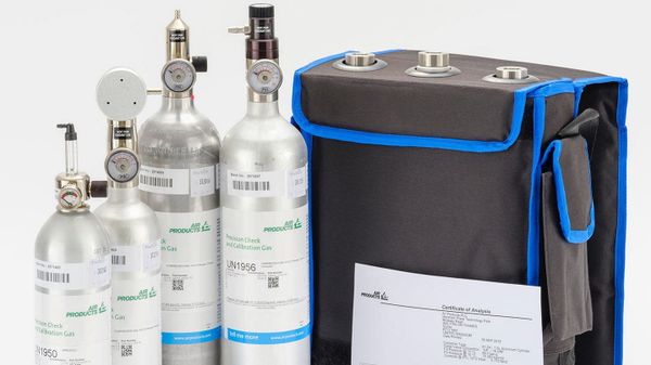 Homem usando um detector de gases portátil em um ambiente industrial, realizando um teste de verificação funcional.