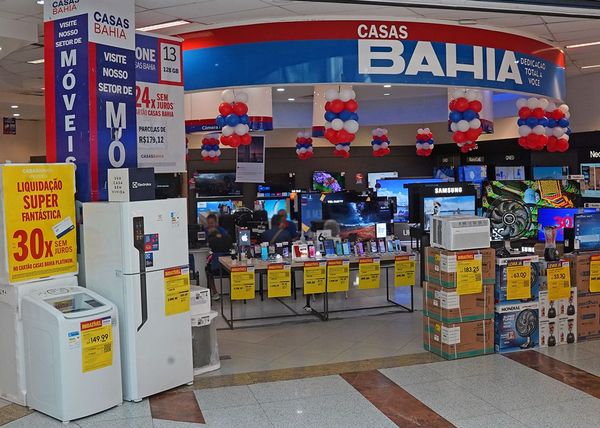 Interior de uma loja da Casas Bahia com eletrodomésticos e eletrônicos em exposição, balões decorativos e cartazes de ofertas