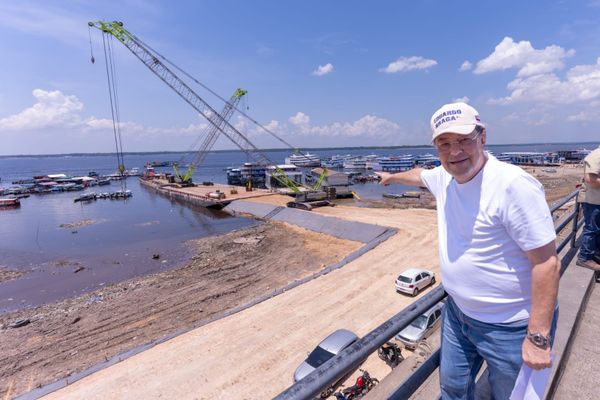Senador Eduardo Braga aponta para canteiro de obras com guindastes na orla do Rio Negro, em Manaus.